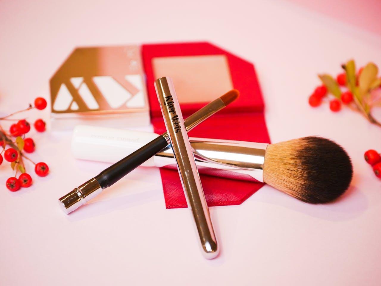 gallery-6 Stylish arrangement of makeup brushes and tools with decorative red berries, perfect for beauty and cosmetics themes.