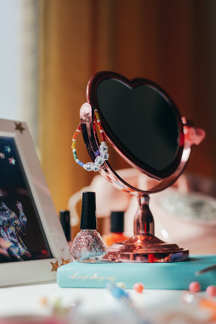 services-02 A stylish vanity setup featuring a heart-shaped mirror, nail polish, and colorful beads.