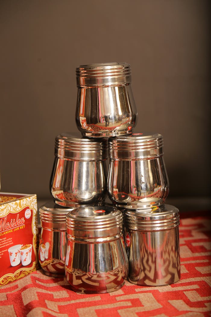 A neat stack of reflective stainless steel containers on a patterned surface.