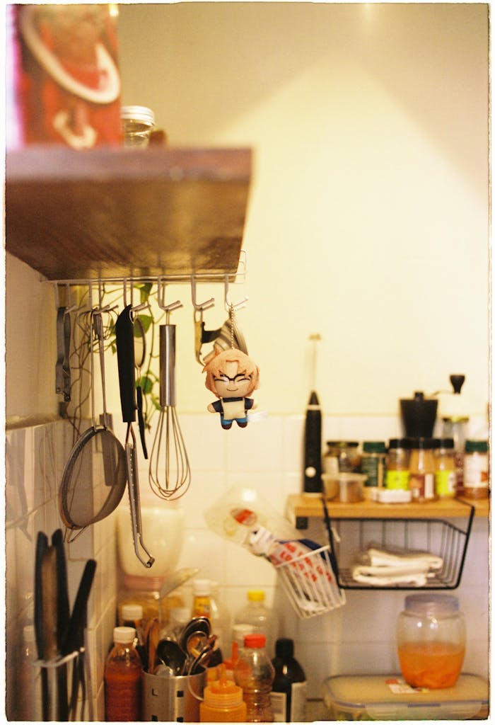 A warm kitchen scene with hanging utensils, spices, and a plush toy for a homely feel.